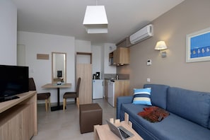 A compact living space with a television, a sofa, a dining area, and a kitchenette. - Apartment in Le Lotus Blanc with Sea View (Le Barcares)
