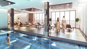 A modern indoor pool area with lounge chairs and a view of the sea. - Chalet in Paradiski with Pool & Spa (Plagne Villages)