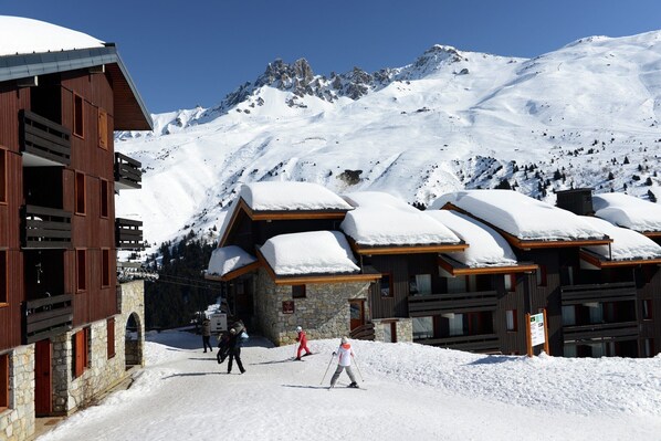 A snow-covered mountain lodge with wooden architecture and ski slopes in the background.