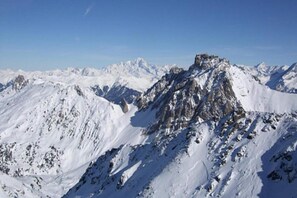 A snow-covered mountain range with rugged terrain and rocky peaks.