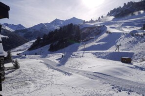 A snow-covered mountain landscape with ski slopes, a ski lift, and a building with a sloped roof.