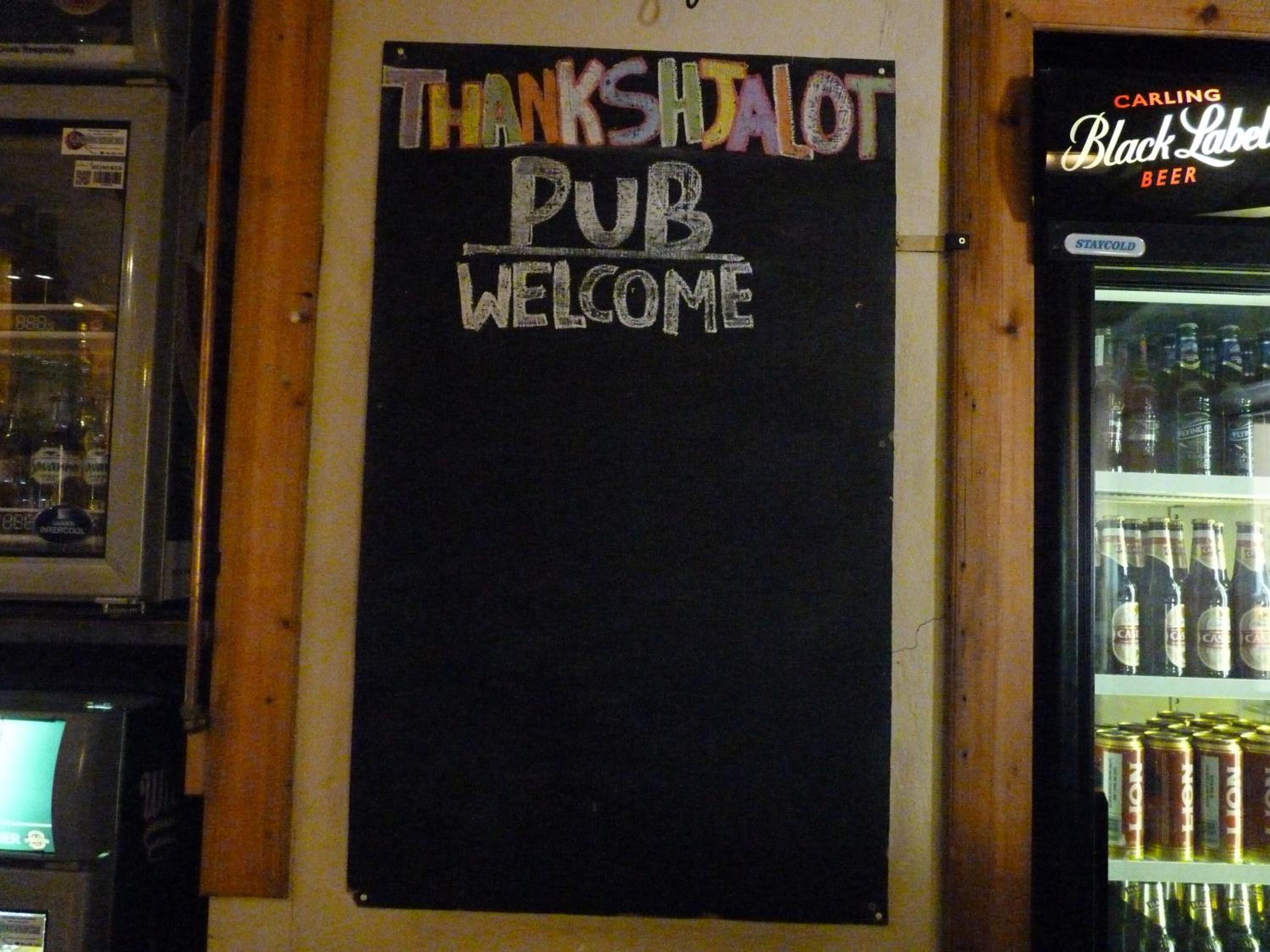 A chalkboard sign with "THANKSIDALOT PUB WELCOME" written on it.