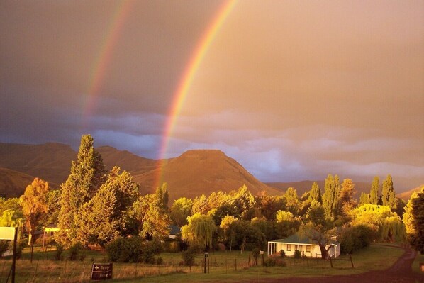 A rural landscape with a rainbow, a house, and a sign indicating 'Barley' and 'Rye'.