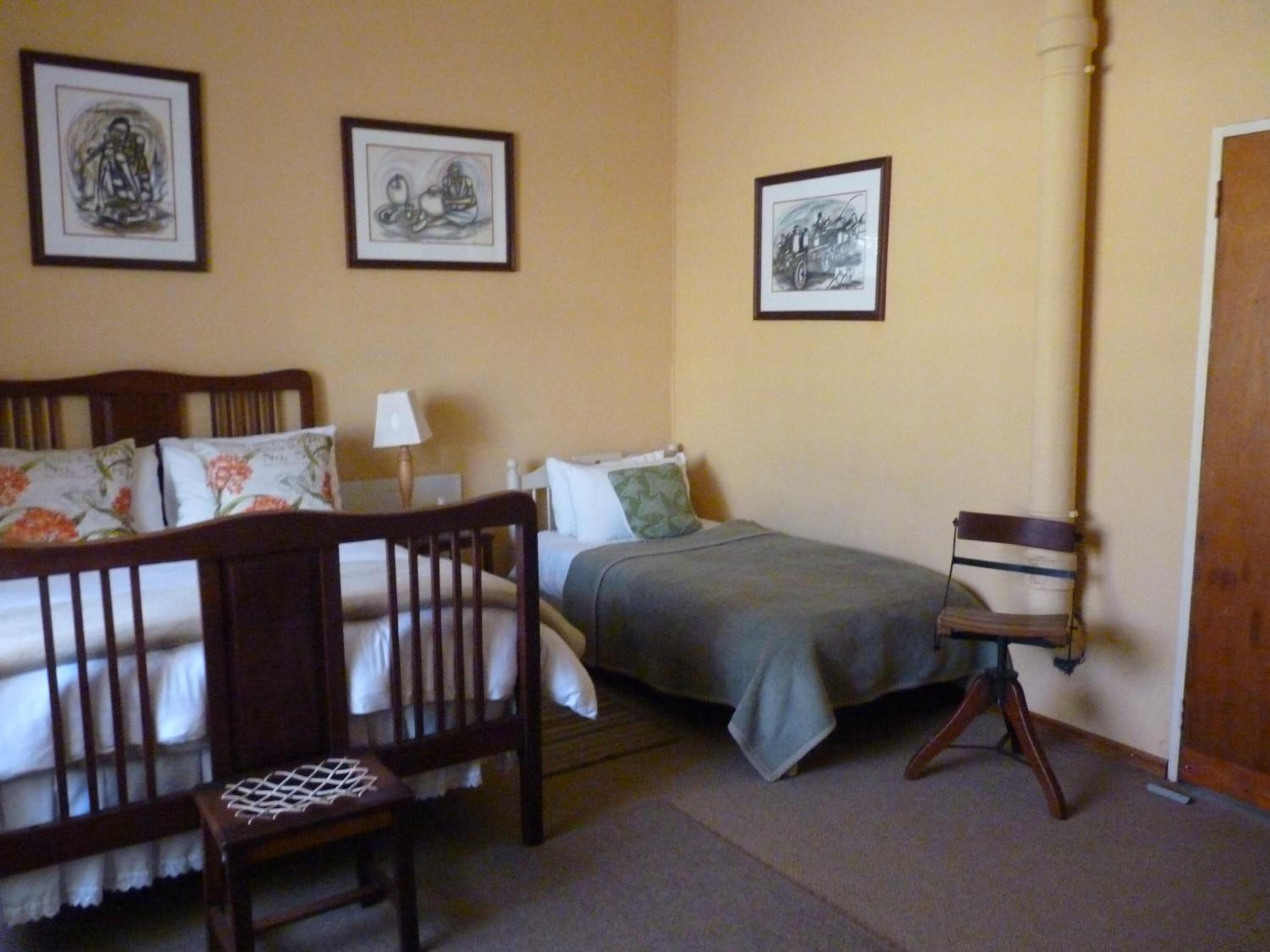 A bedroom with a bed, a chair, and three framed pictures on the wall.