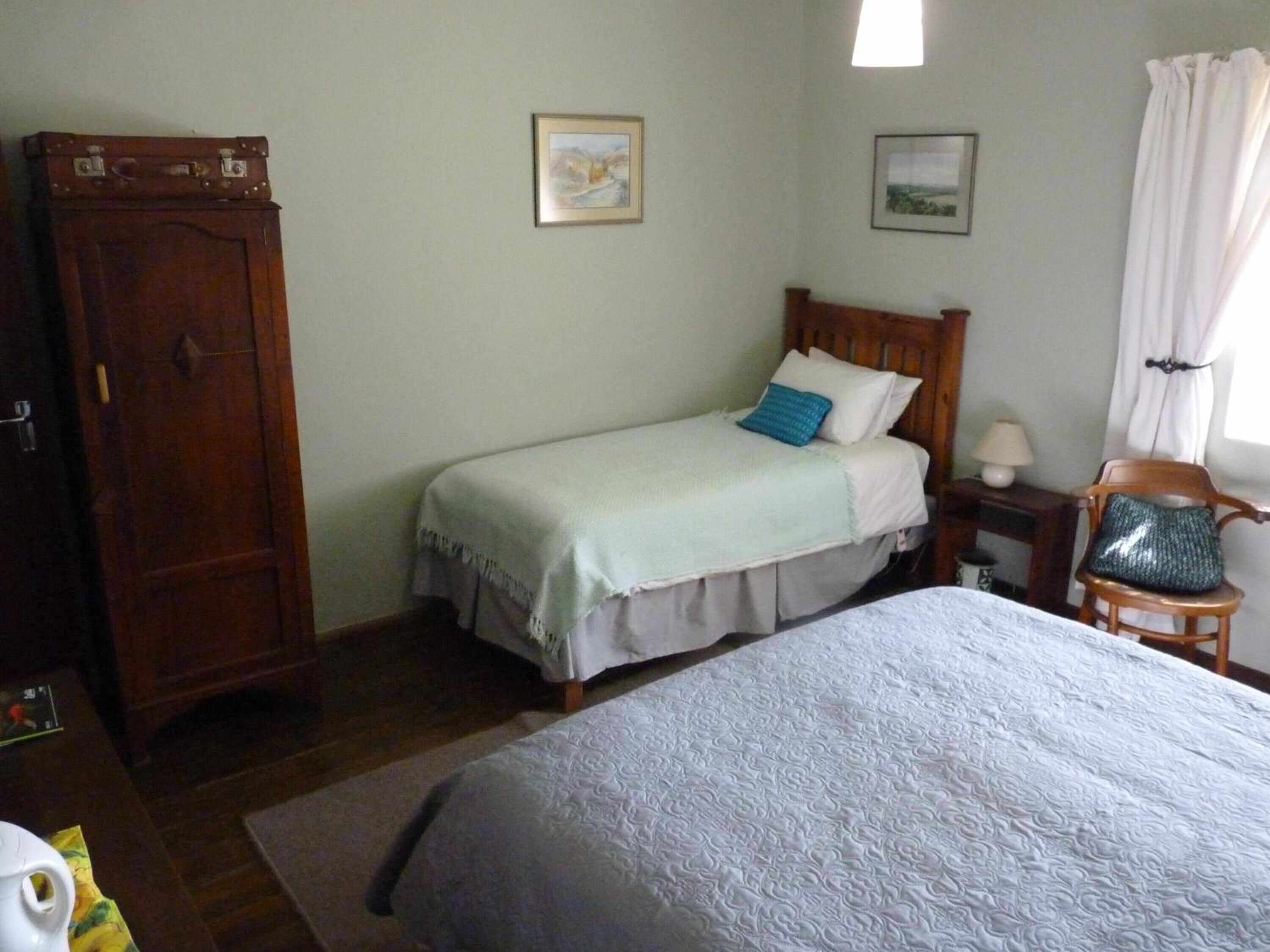 Un dormitorio con dos camas, un armario de madera y dos cuadros en la pared.