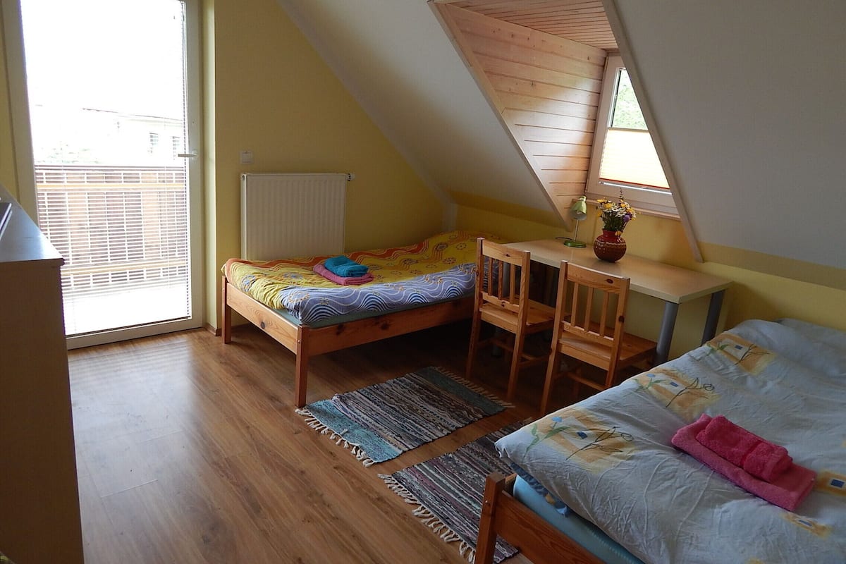 Een knus slaapkamer op zolder met schuine wanden, een enkel bed, een bureau en een radiator.