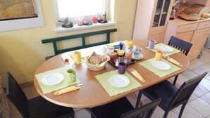Een eettafel gedekt met borden, bestek en een broodmand.