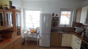 Een keuken met een koelkast, gootsteen, magnetron en houten kastjes.