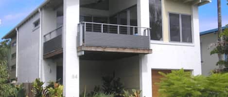 A modern two-story building with a balcony on the ground floor.
