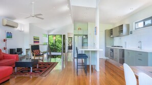 A modern living space with a kitchen, dining area, and a red sofa.