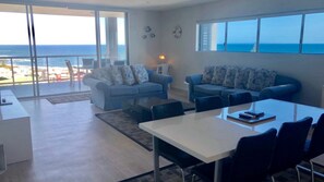 A modern living room with a large sliding glass door leading to a balcony overlooking the sea.