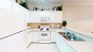 A modern kitchen with white cabinetry, a built-in oven, a microwave, and a stainless steel sink. - Golf Villa in Little River (K102) (Little River)