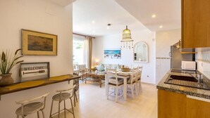 A spacious kitchen with a dining area, featuring a wooden island, white chairs, and a modern chandelier. - Anacasa Zurich Les Marines AP3216 (Denia)