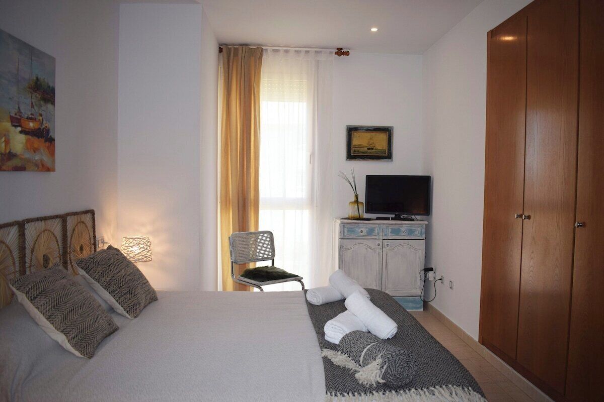 Una habitación de hotel con cama, televisión, armario y ventana con cortinas.