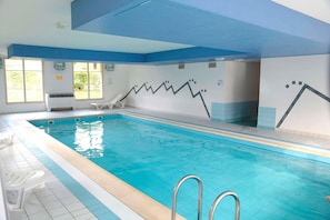 An indoor swimming pool with clear blue water, a white tiled floor, and a pool ladder. - Peaceful Alsace Retreat (Bergheim)