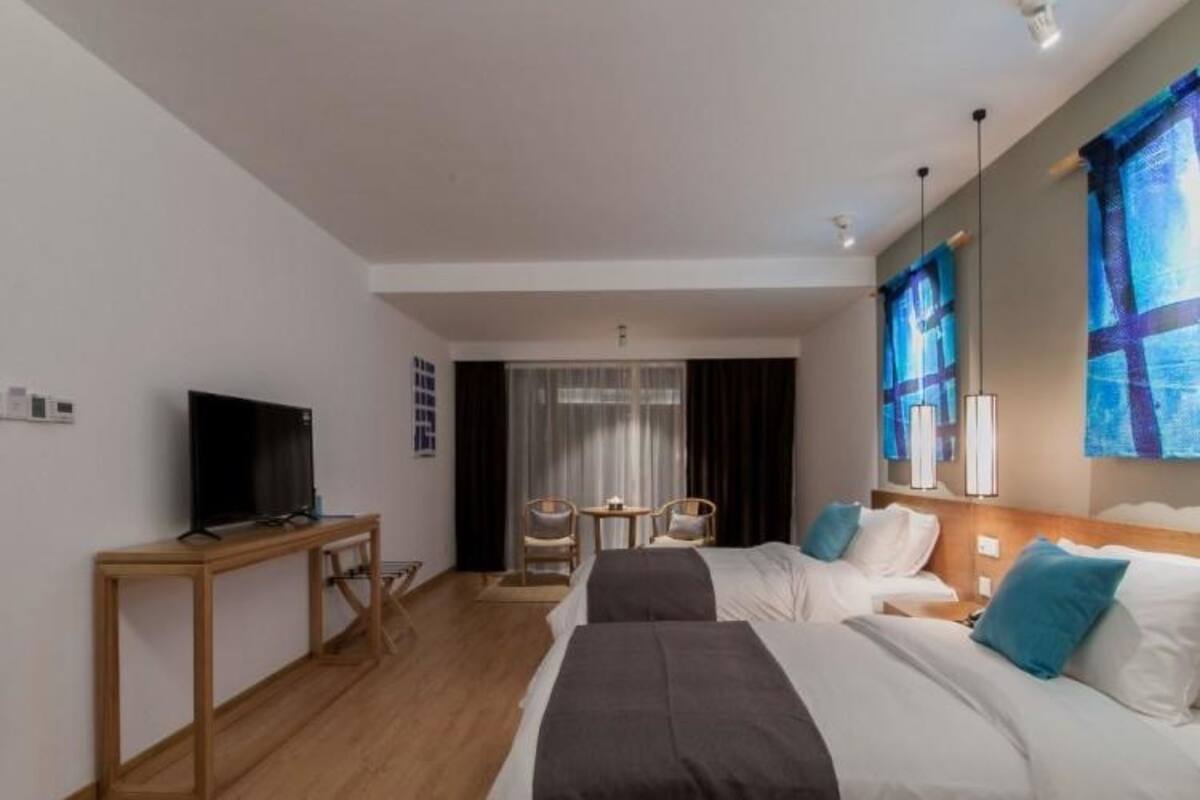 Une chambre d’hôtel avec un lit, un bureau, une télévision et une fenêtre avec des rideaux.