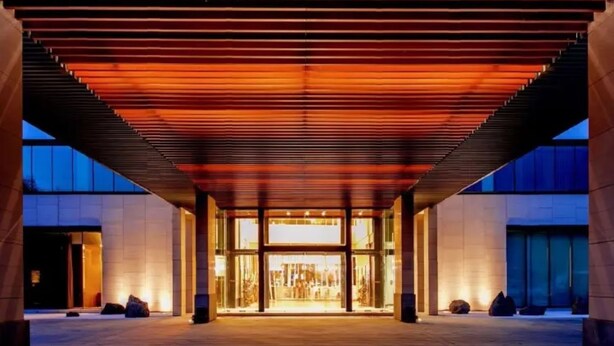 Une entrée moderne, avec un passage couvert et des portes en verre.