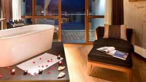 Une chambre dotée d’une grande baignoire, d’un lit et offrant une vue sur l’extérieur.
