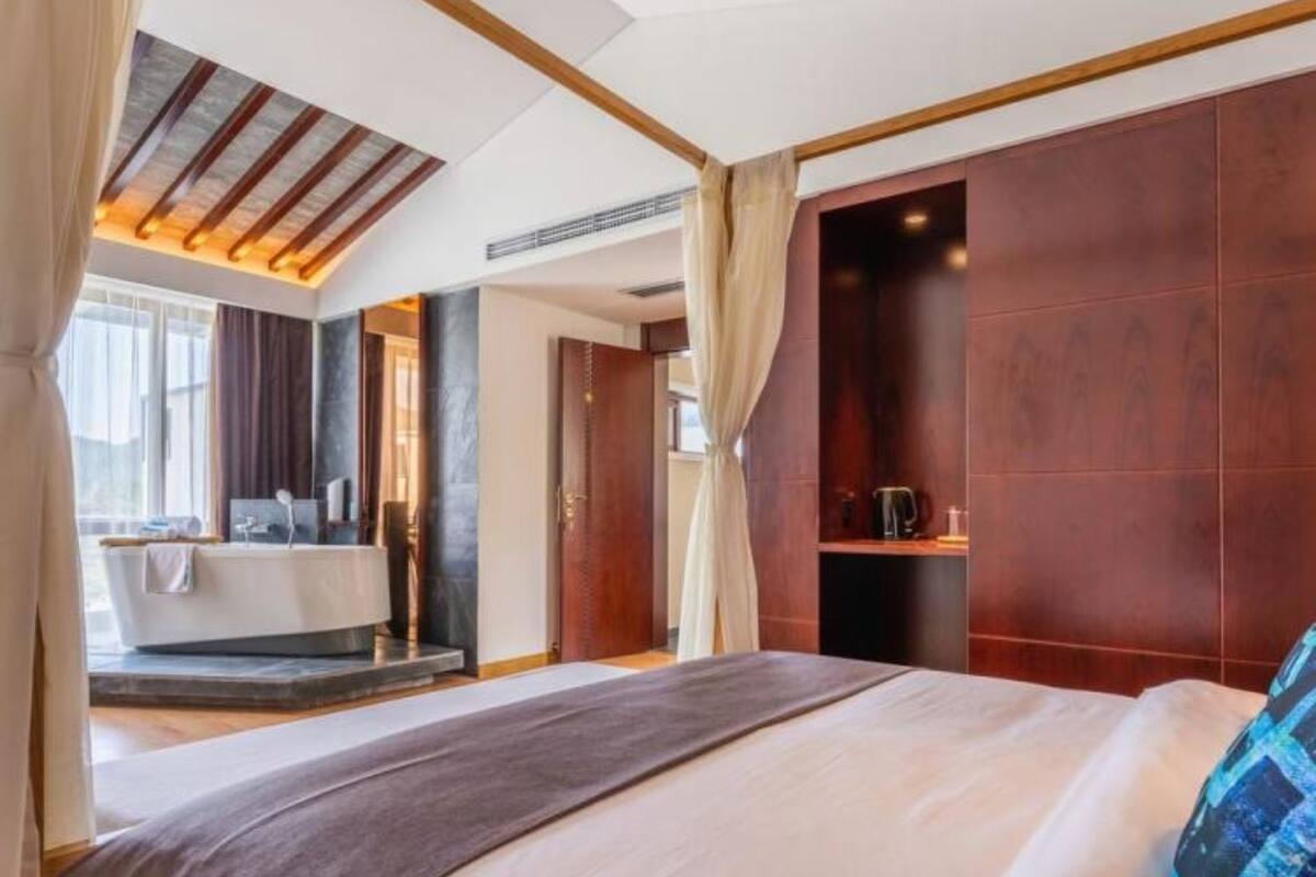 Une chambre d’hôtel moderne avec un grand lit, une salle de bain avec baignoire et une vue sur la ville.