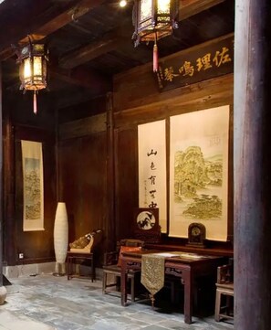 A traditional room with wooden beams, a large calligraphy scroll, and a wooden table with chairs.