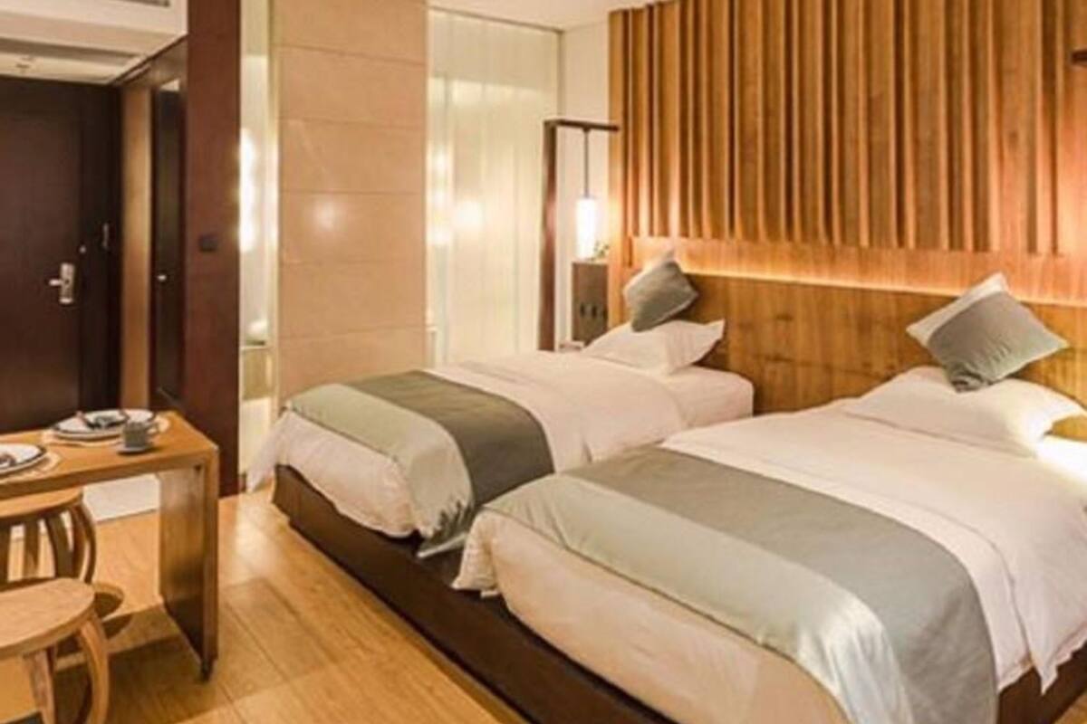 Une chambre d’hôtel avec deux lits, une tête de lit en bois, un bureau et une chaise.
