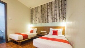 A hotel room with two beds, a wooden headboard, a patterned wall, and a wooden floor. - Reddoorz Plus @ Celaket (Malang)