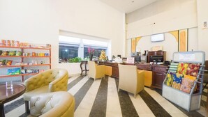 A hotel lobby with a striped floor, a reception desk, a television, and a vending machine. - Reddoorz Plus @ Celaket (Malang)
