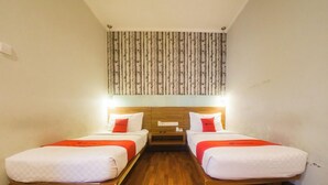 A hotel room with two single beds, wooden headboards, a wall-mounted light fixture, and a patterned wallpaper. - Reddoorz Plus @ Celaket (Malang)