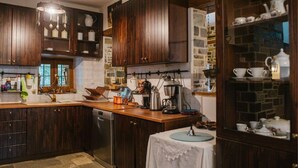 A kitchen with dark wooden cabinets, a stone backsplash, and a coffee station. - Eudora - Mansion (Zagora-Mouresi)