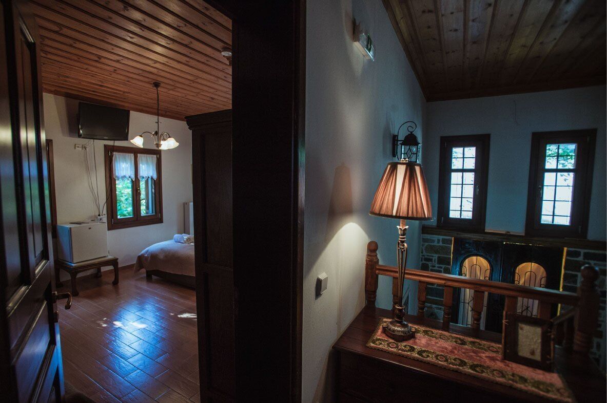 Una habitación con techo de madera, una cama, una mesa con lámpara y una chimenea.