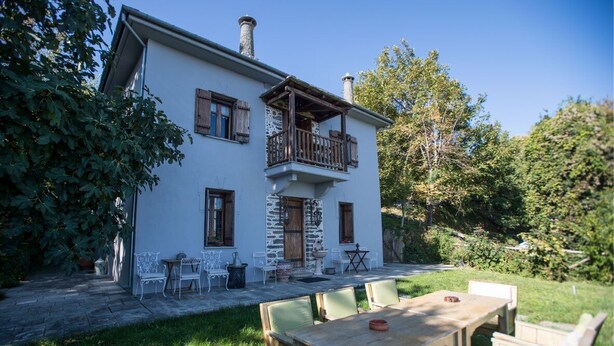 A two-story house with a balcony, stone walls, and a garden with outdoor furniture. - Eudora - Mansion (Zagora-Mouresi)