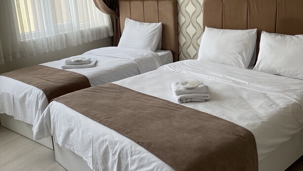Une chambre d’hôtel avec deux lits, un mur décoré de motifs et une fenêtre avec des rideaux.