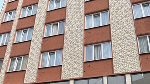 Un immeuble à plusieurs étages, doté d’une façade ornée de motifs, de grandes fenêtres et d’un toit plat.