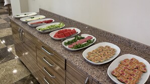 Un buffet proposant une variété d’aliments, notamment des pastèques, des concombres et des en-cas emballés.