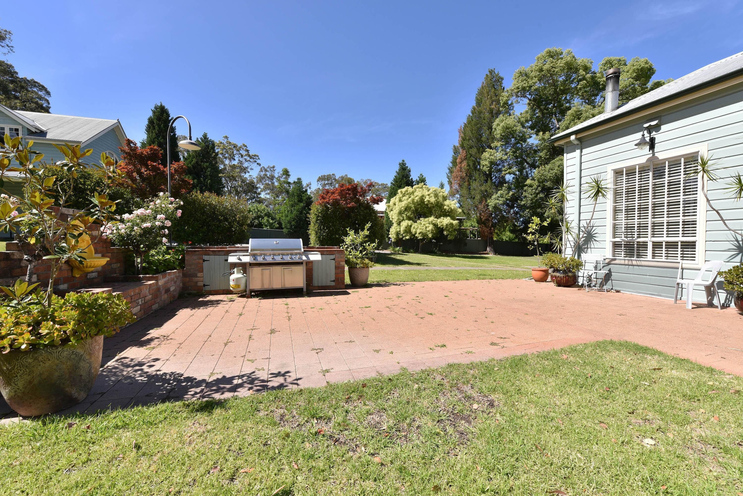 A backyard with a barbecue area, a brick patio, and a lawn.