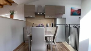 A compact kitchen with a dining area, wooden flooring, and a small potted plant. - B&B La Casa dei Miraglia San Cataldo (San Cataldo)