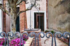 A courtyard with a brick wall, a metal bench, and a tree with flowers. - B&B La Casa dei Miraglia San Cataldo (San Cataldo)