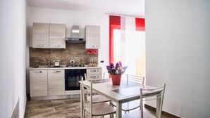 A modern kitchen with light wood cabinets, a gas stove, and a dining area with a table and chairs. - B&B La Casa dei Miraglia San Cataldo (San Cataldo)