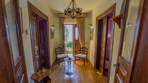 A narrow hallway with wooden flooring, two wooden doors, a chandelier, and a small round table with chairs. - Guesthouse Ellis (Zagora-Mouresi)