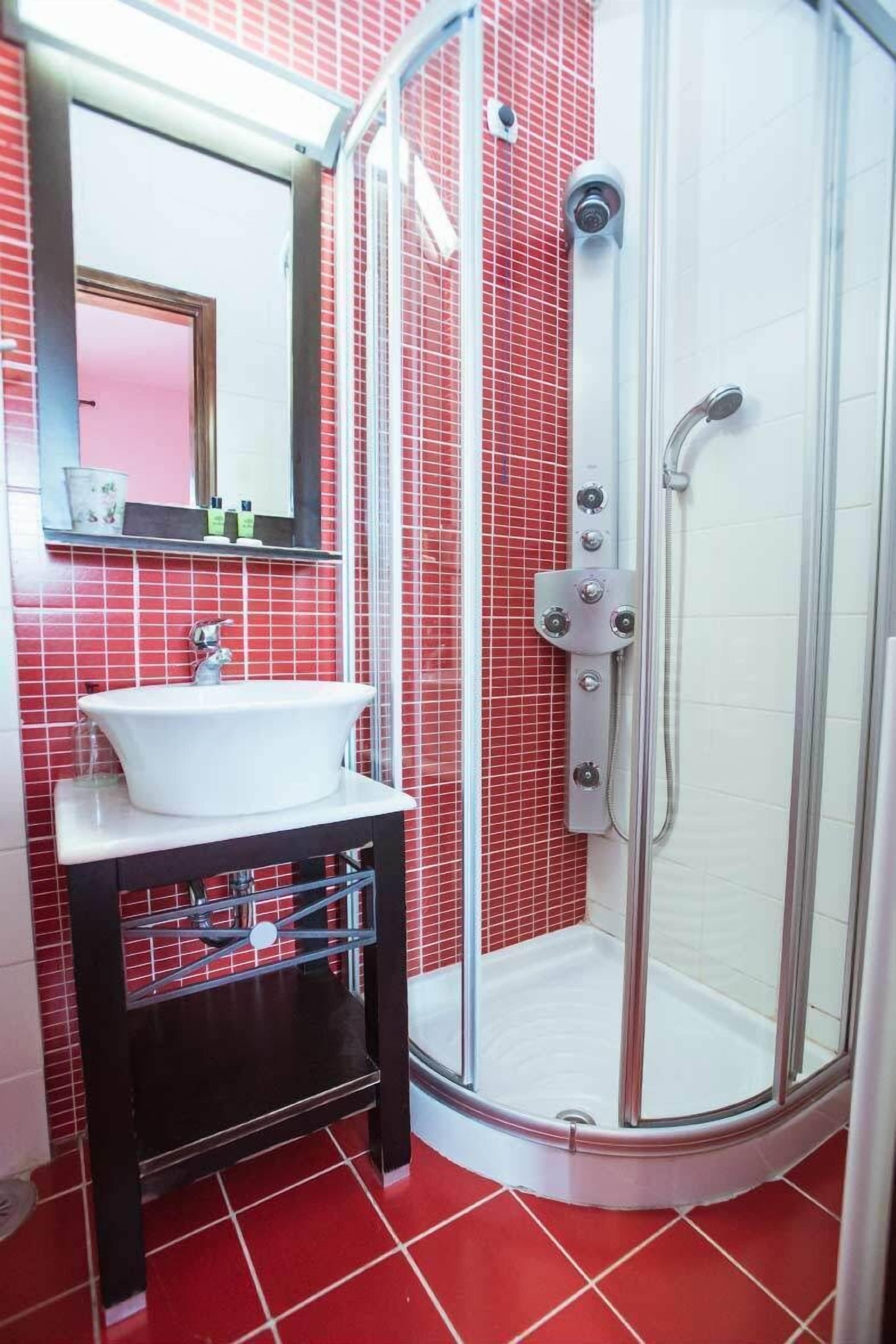 Une salle de bain avec un lavabo blanc, un miroir et une douche à parois de verre.