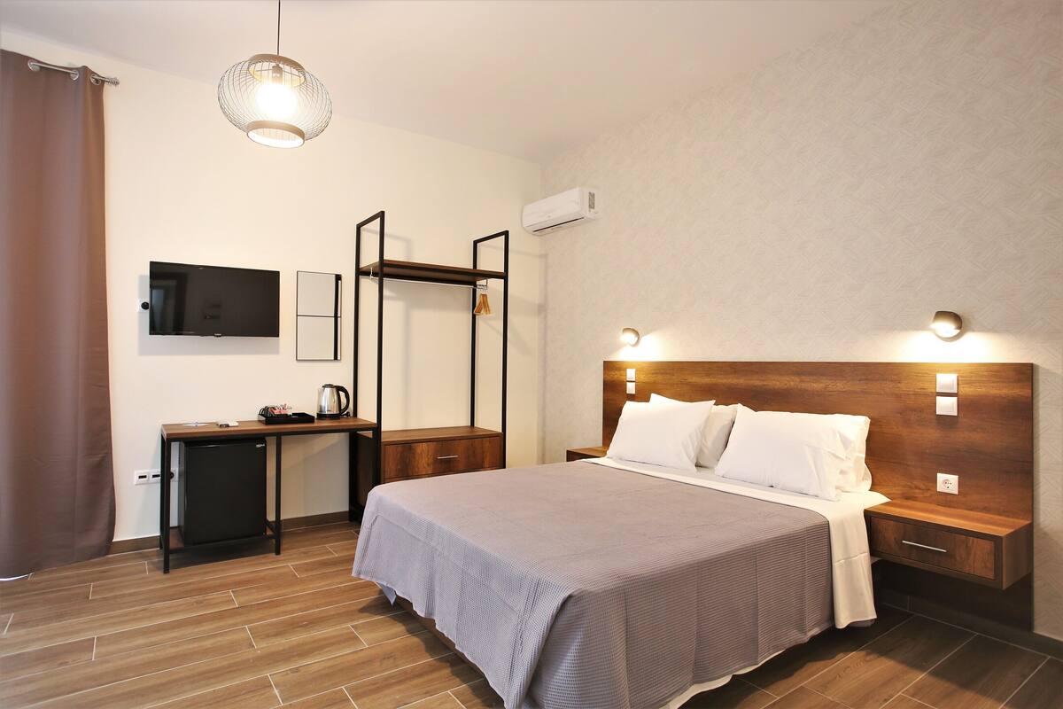 Une chambre d’hôtel équipée d’un lit, de tables de chevet, d’un bureau, d’une chaise, d’une télévision et d’un appareil de climatisation.