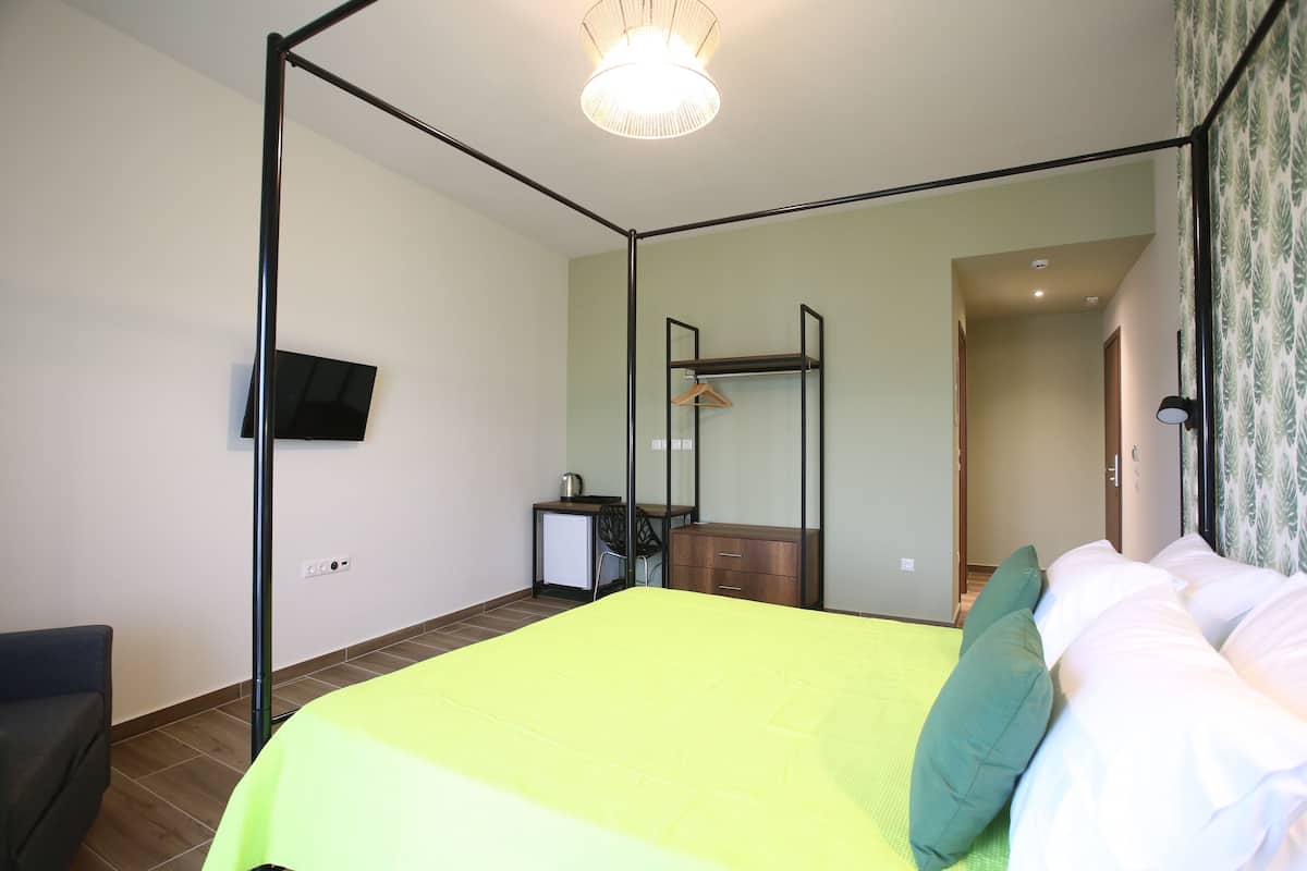 Une chambre avec un lit, un bureau, une chaise, une armoire et un téléviseur fixé au mur.