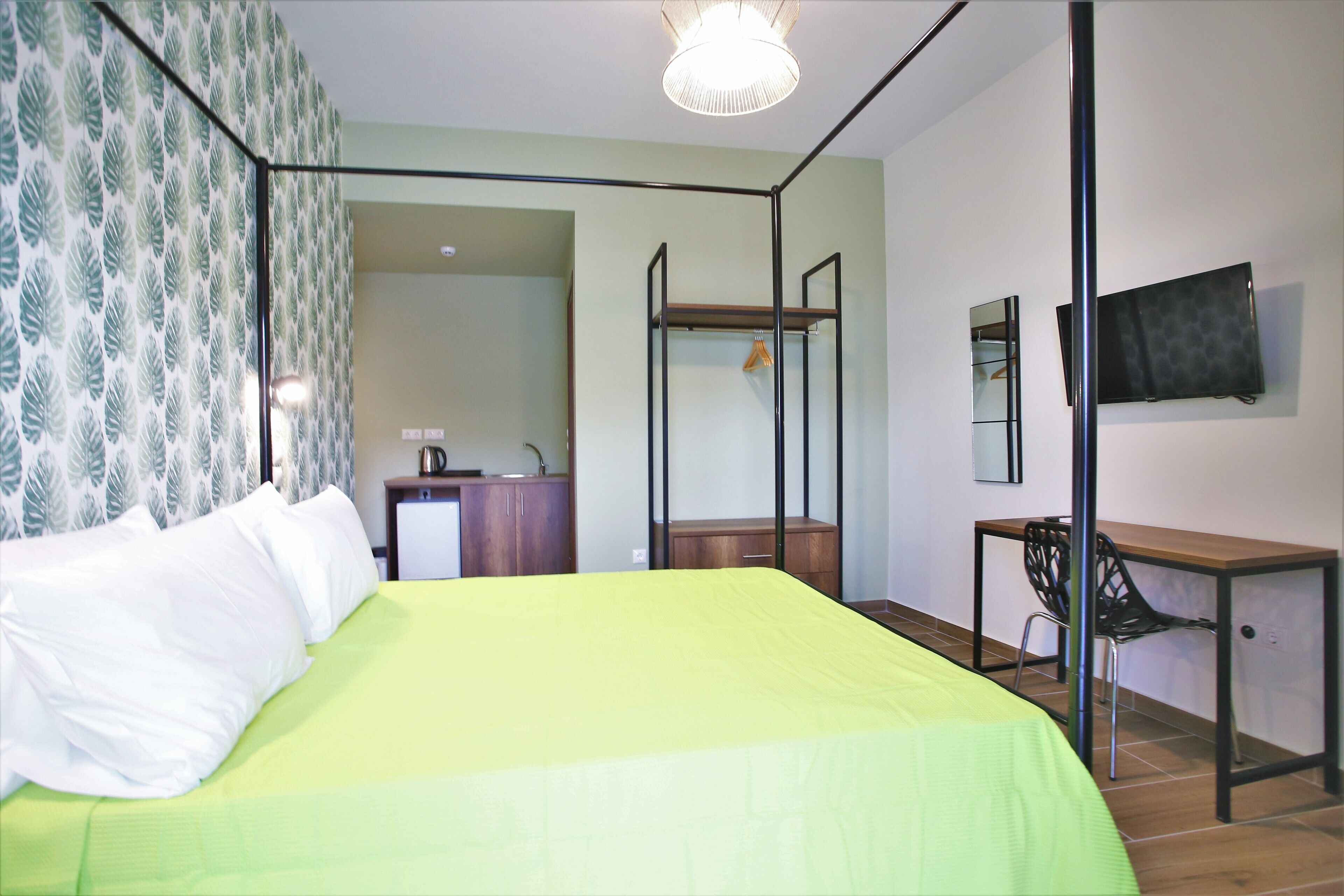 Une chambre avec un lit, un bureau, une chaise, une télévision et une armoire.