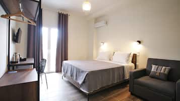 Un dormitorio con cama, mesita de noche, silla y escritorio con perchero.