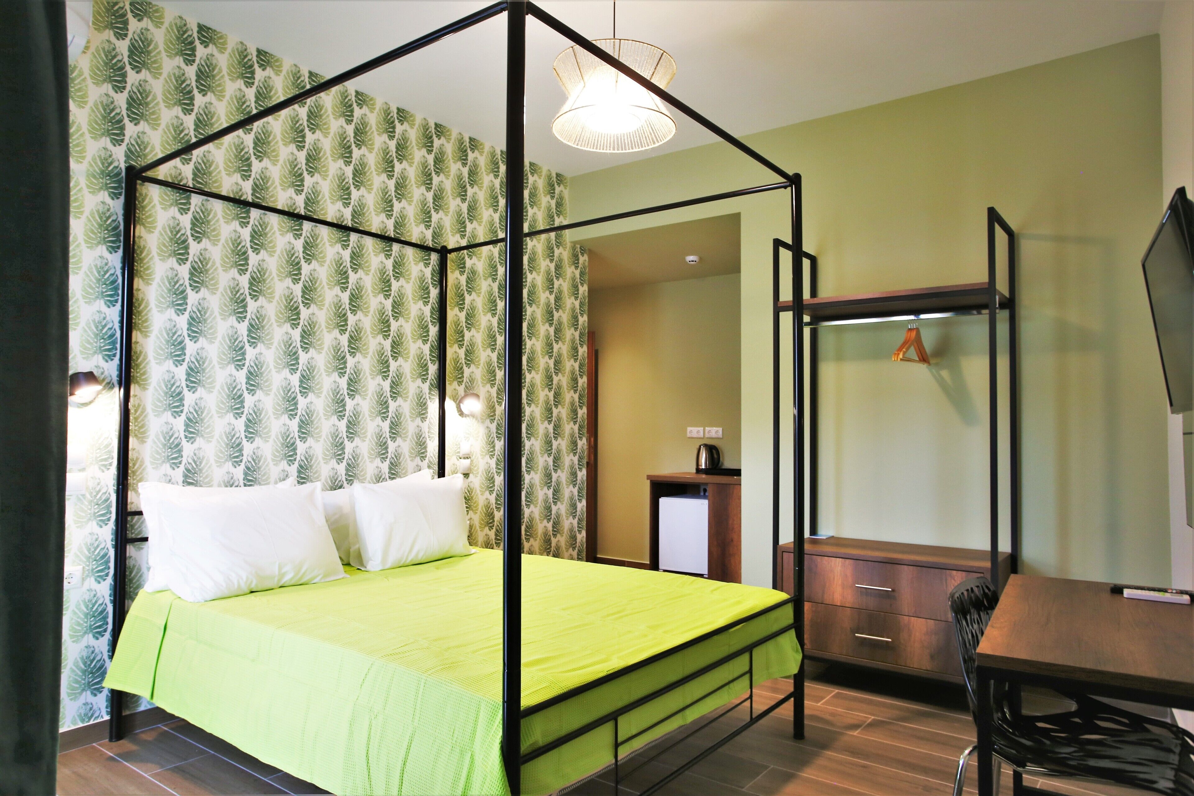A room with a four-poster bed, a desk with a chair, a television, and a wardrobe.