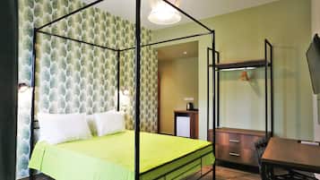 A room with a four-poster bed, a desk with a chair, a television, and a wardrobe.