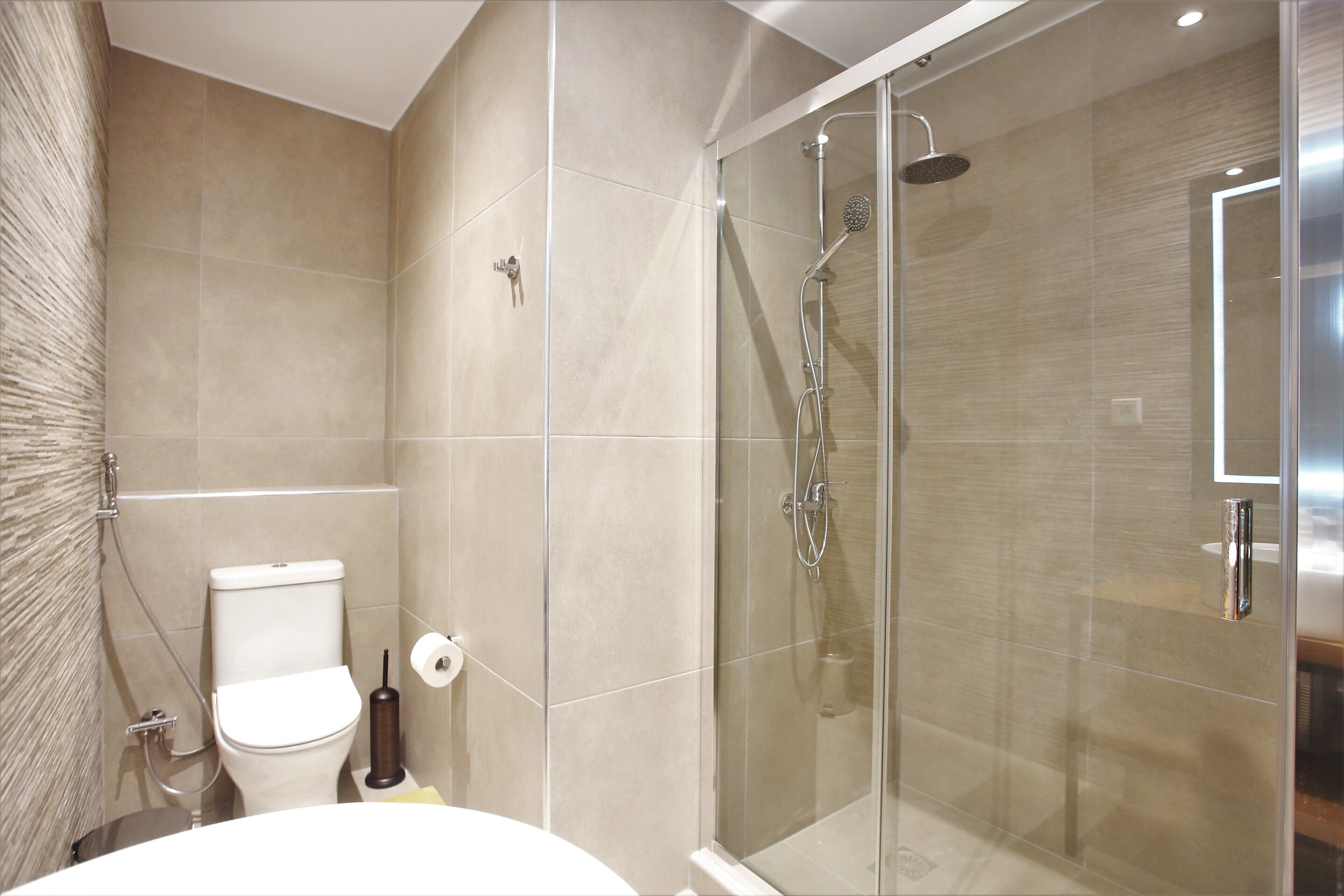A bathroom with a glass-enclosed shower, a toilet, and a sink.
