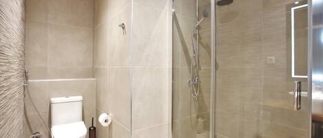 Un baño con ducha de vidrio, inodoro y lavamanos.