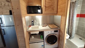 A compact kitchen with a microwave, sink, and washing machine.