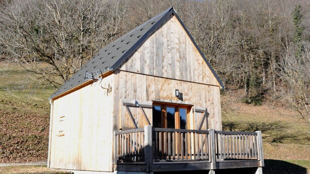 A wooden cabin with a sloped roof, a front porch, and a small window.